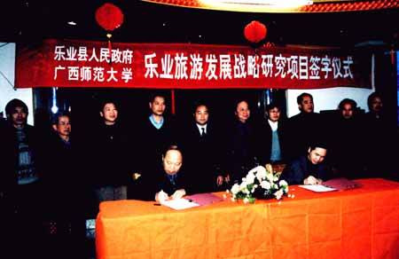 图为我校党委副书记、旅游研究所所长阳国亮（左）与乐业县县长周武红分别在协议上签字。