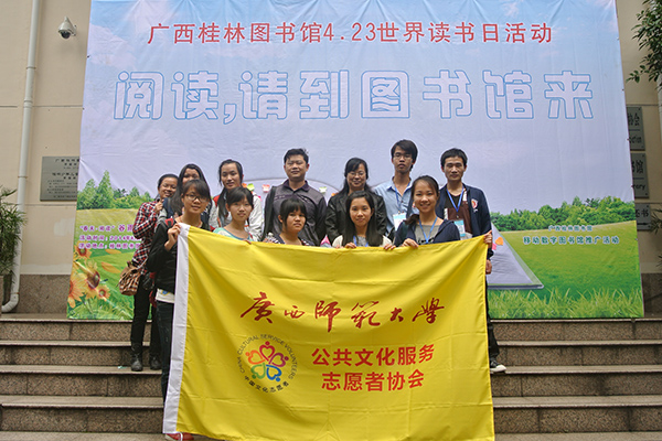 公共文化服务志愿者在主题活动宣传栏前合影