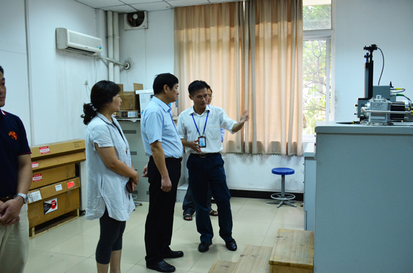 工作人员向卢能干一行介绍实验设备