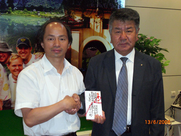 生田健一社长（右）向易忠副校长赠送赈灾捐款。
