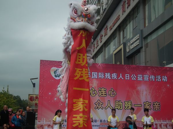 舞狮表演为现场展示“众人助残一家亲”横幅