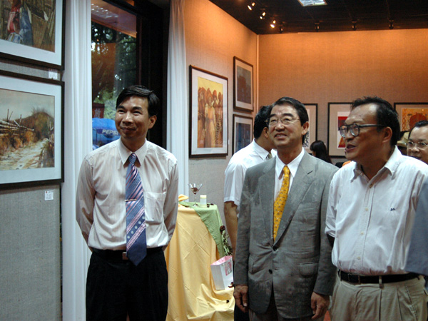 在梁宏校长的陪同下，崇城大学的客人们出席了美术系2004届毕业生作品展。（赵亮 图）