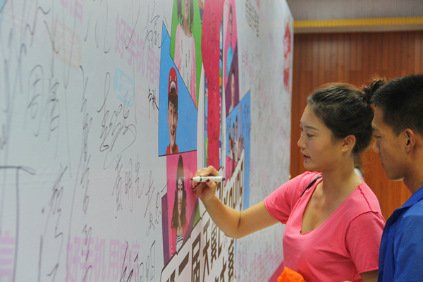 现场观众在签名墙上签名，为选手加油